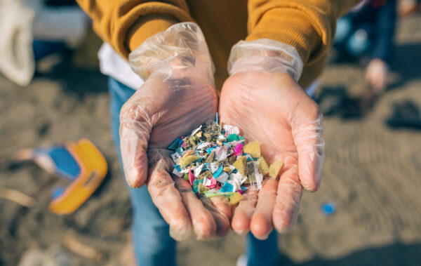 Persona muestra en sus manos microplásticos en la playa.